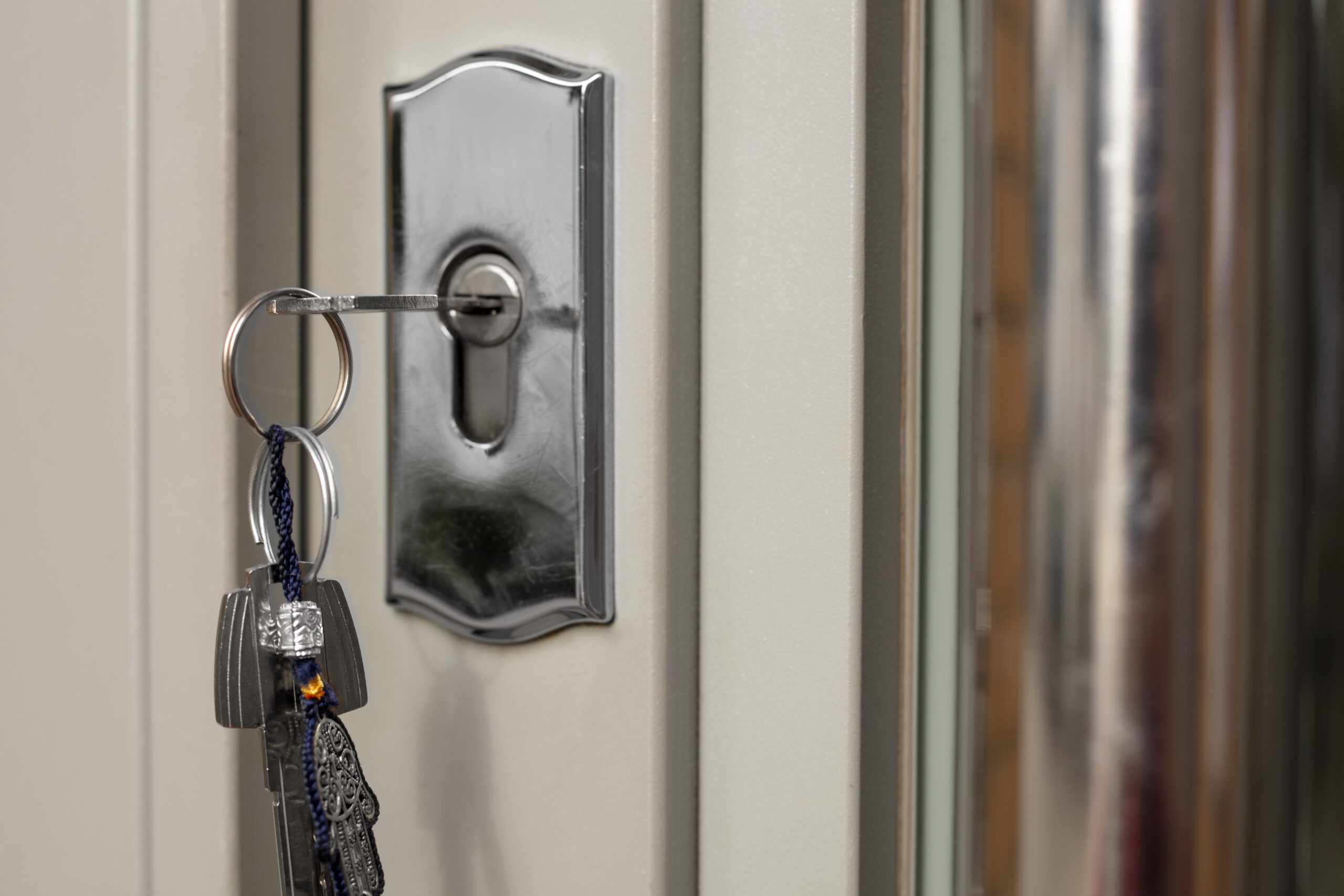 A metallic key inserted in a modern door lock with keychain.