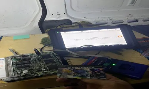 Technician with a tablet and laptop, engaged in Car Key Transponder (Re)Programming for automotive locksmith solutions.
