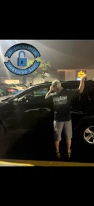 technician from A1 Locksmith Services, LLC, posing next to a black car in a parking lot, showcasing the locksmith services provided for automotive needs
