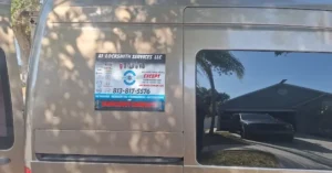 The side of a van displaying the logo and contact information for A1 Locksmith Services LLC, offering residential, commercial, automotive, and emergency lockout services. The van is parked outdoors with a clear view of the house in the background.