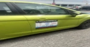 Green car with a signboard on the side, featuring a contact number and service details. Tip to choose an automotive locksmith for fast and reliable service.