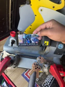 A1 Locksmith Services LLC technician uses a key-cutting machine with several keys and a business card displayed, showcasing professional residential lock replacement service.