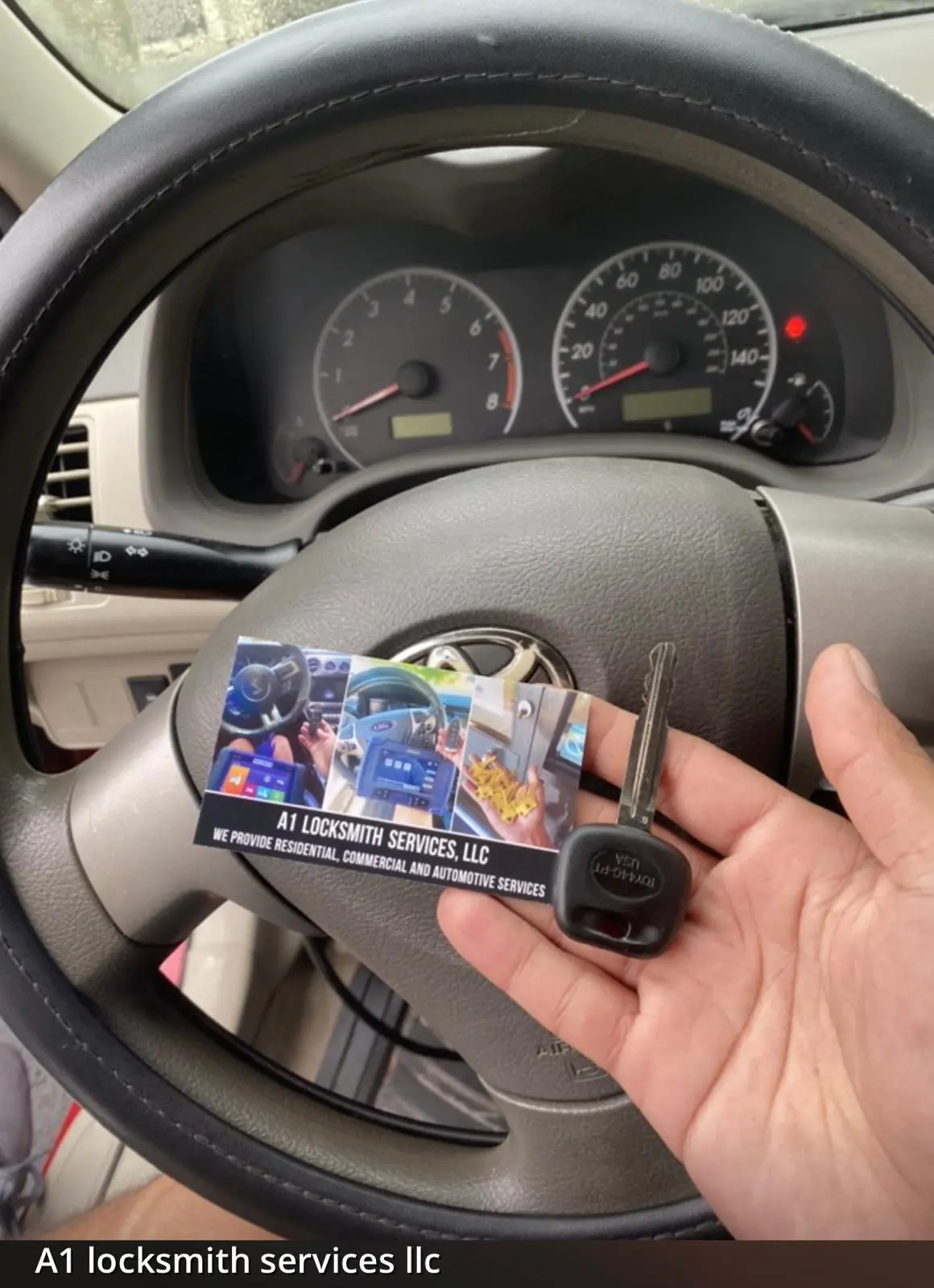 A1 Locksmith Services LLC technician holds a Toyota car key and business card inside a vehicle, representing professional ignition repair service and automotive locksmith expertise.